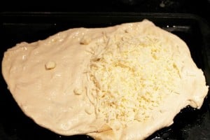 Add cheese to one hlaf cirlce of pizza dough for homemade calzone
