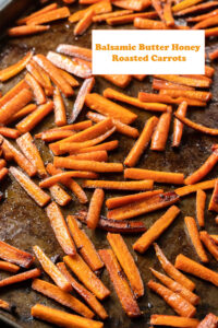 roasted carrot sticks on baking tray white rectangle in top right with orange lettering says balsamic butter honey roasted carrots